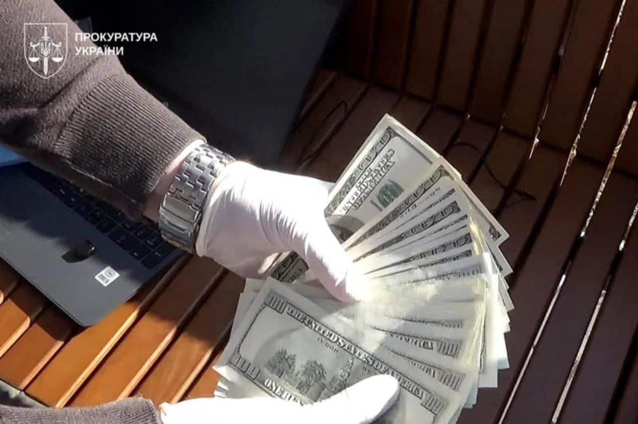 Слідчий у рукавичках тримає пачку доларів — речовий доказ хабара під час затримання полковника Нацгвардії