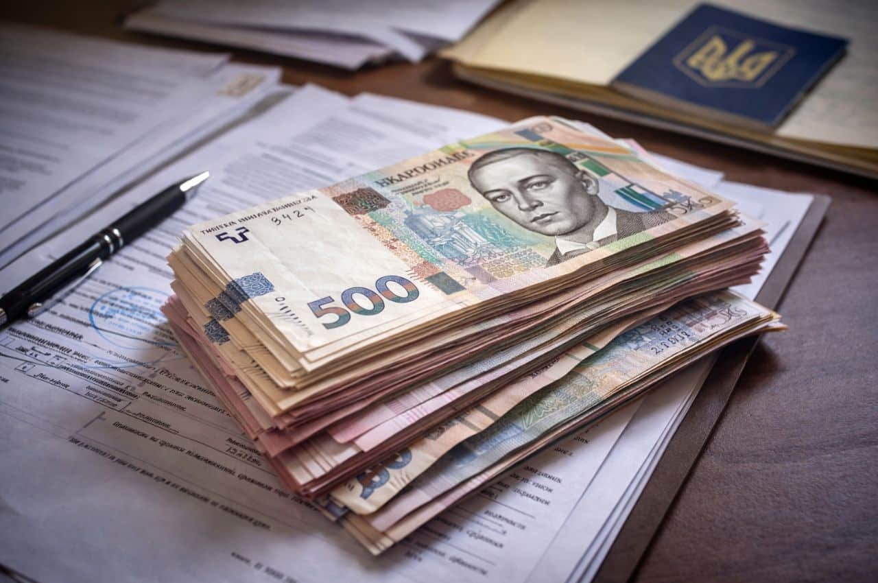 Пачка українських гривень на офіційних документах з печатками — ілюстрація корупційної схеми