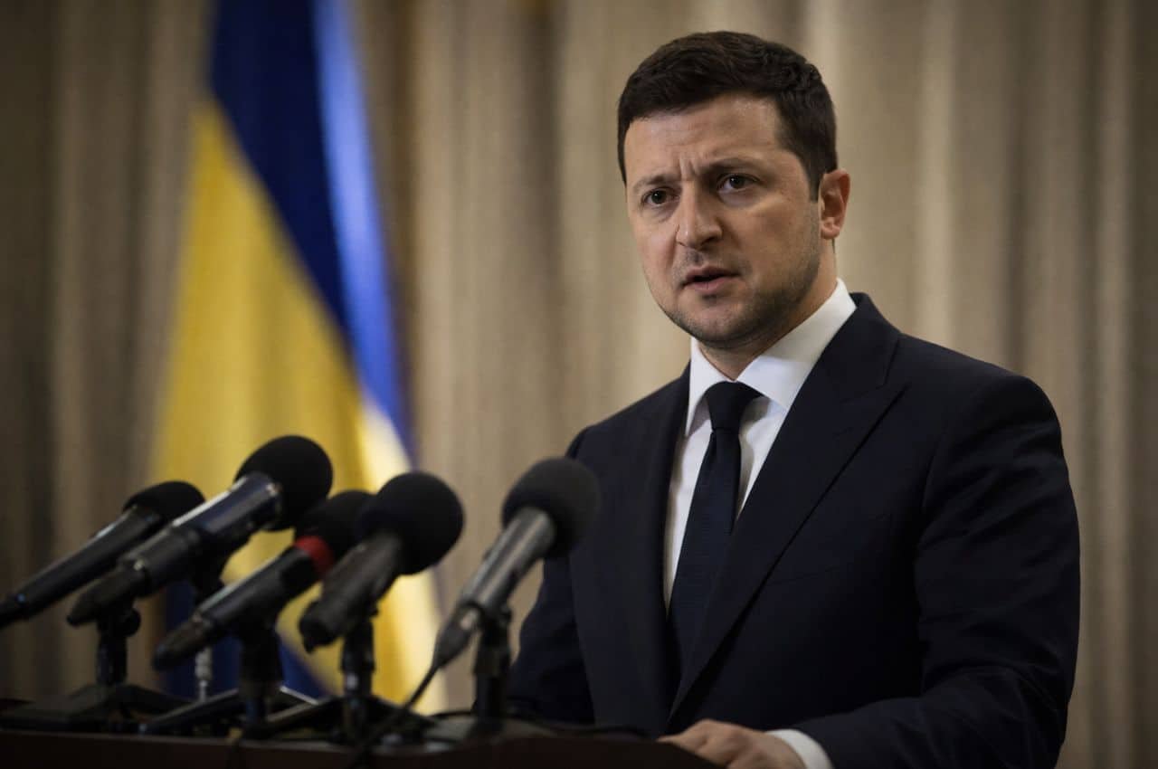 Президент України виступає перед мікрофонами на тлі українського прапора