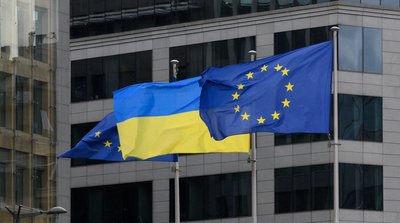 Представники ЄК обговорюють кредит ЄС Україна на тлі прапорів Євросоюзу та України